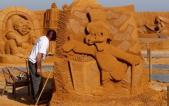 Sand carver Shanin works on a sculpture during the Sand Sculpture Festival "Disney Sand Magic" in Ostend